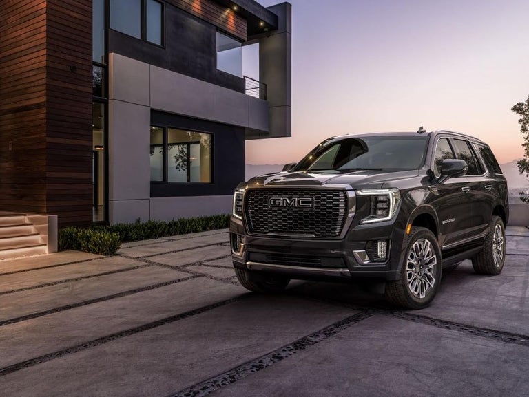 A Black 2024 Yukon XL parked in front of a modern home during sunset